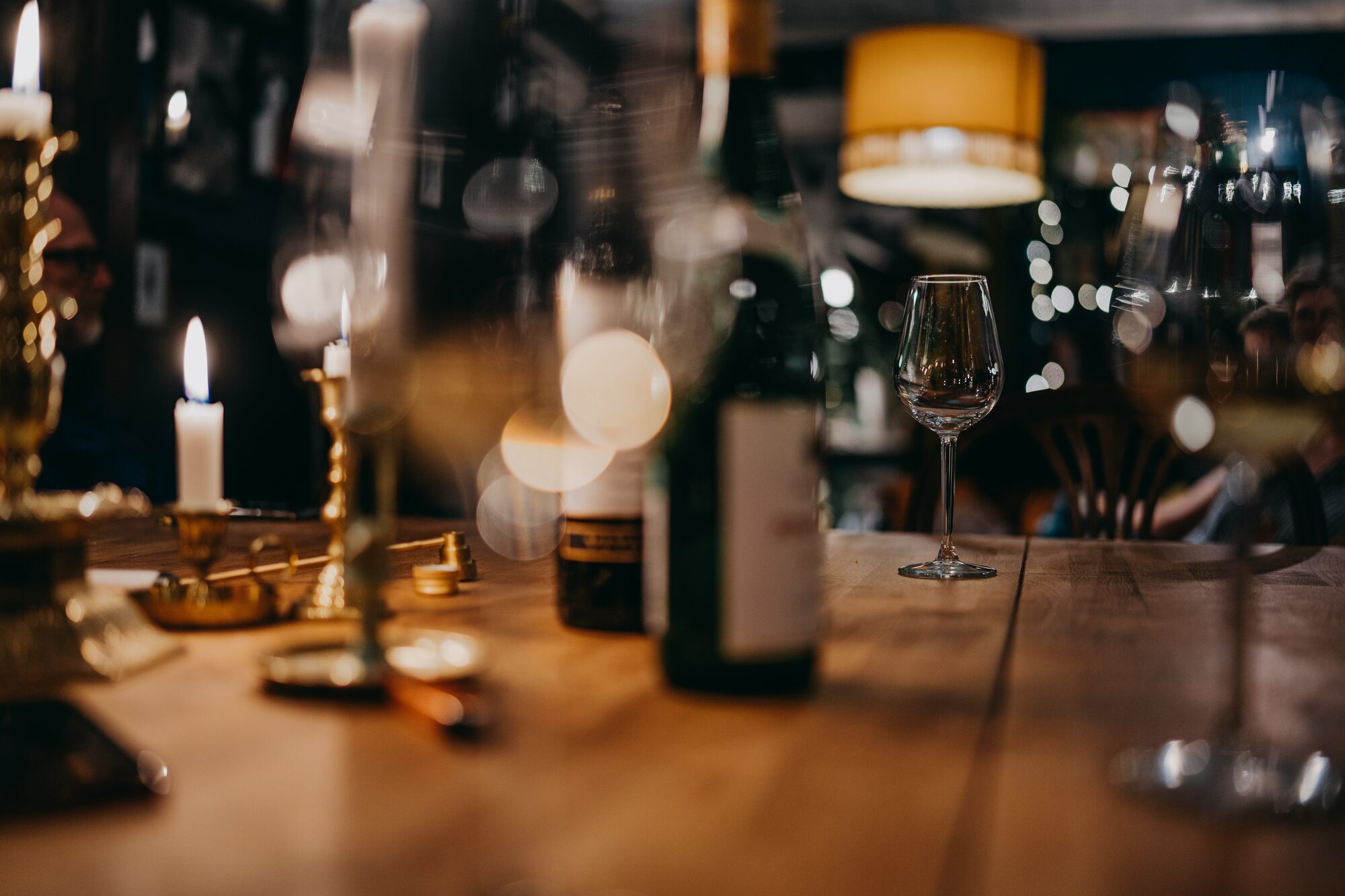 Een glas en fles rode wijn op tafel in warm kaarslicht